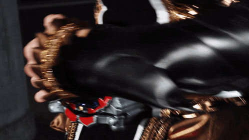 a person wearing a black glove is holding a gold chain
