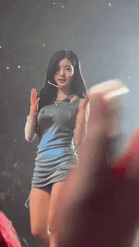 a woman in a blue dress stands on a stage with a microphone