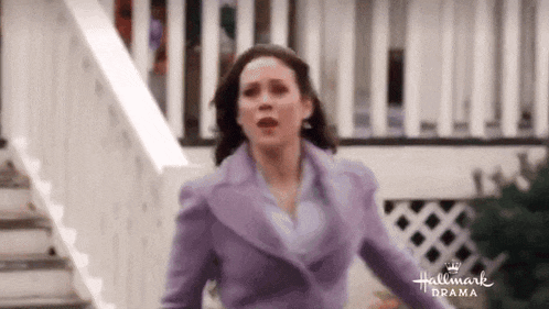 a woman in a purple suit is running down stairs in front of a house .