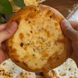 a person is holding a pizza in their hands with a bite taken out of it .