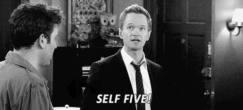 a man in a suit and tie is standing next to another man in a room and says `` self five '' .