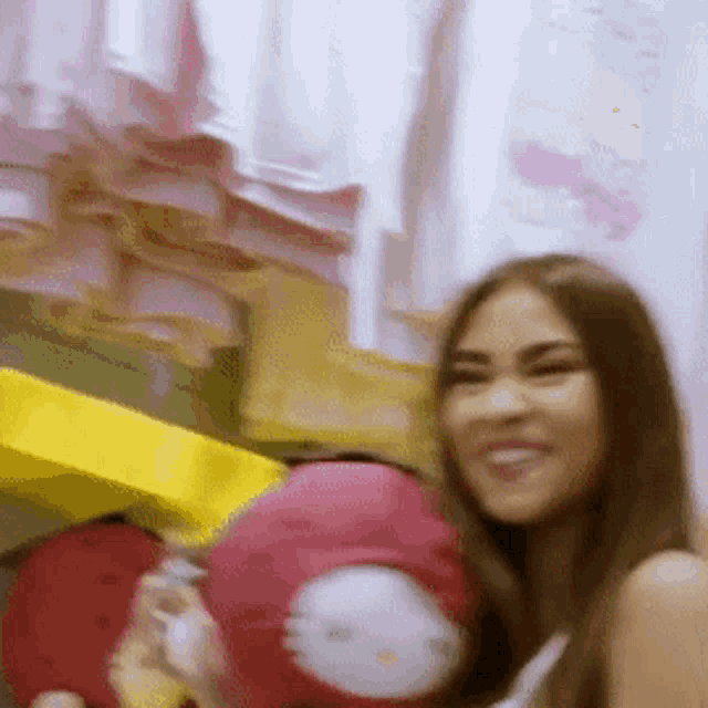 a woman holding a hello kitty pillow and smiling