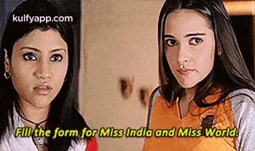two women are standing next to each other and one of them is talking about miss india and miss world .