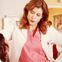 a woman in a pink scrub top and a white lab coat is standing next to a woman in a pink scrub top .