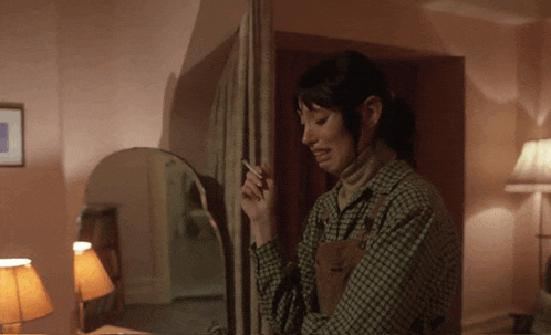 a woman smoking a cigarette in front of a mirror in a room