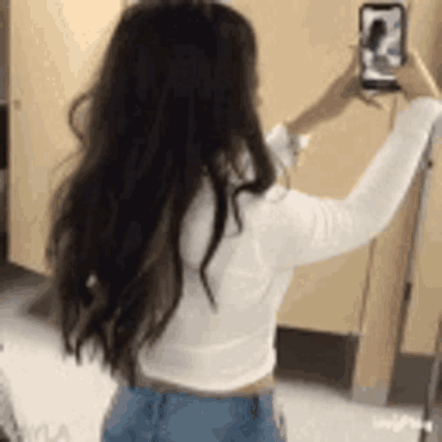 a woman is taking a picture of herself in a public restroom .