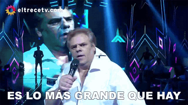 a man singing into a microphone with the words es lo mas grande que hay behind him