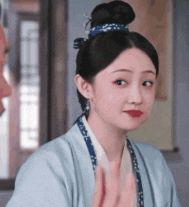 a woman in a blue kimono is making a funny face and waving at someone .