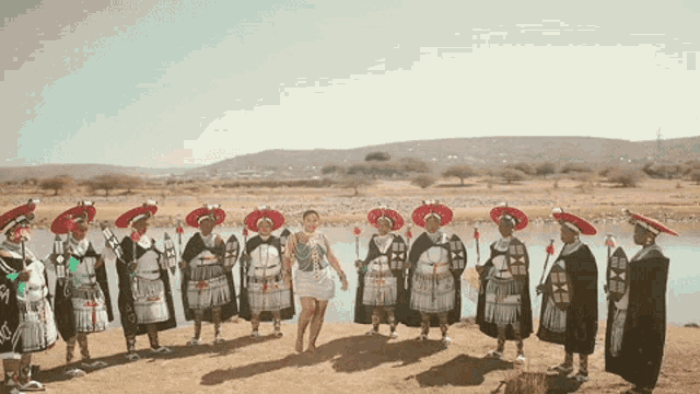 a woman is standing in front of a group of men in traditional costumes