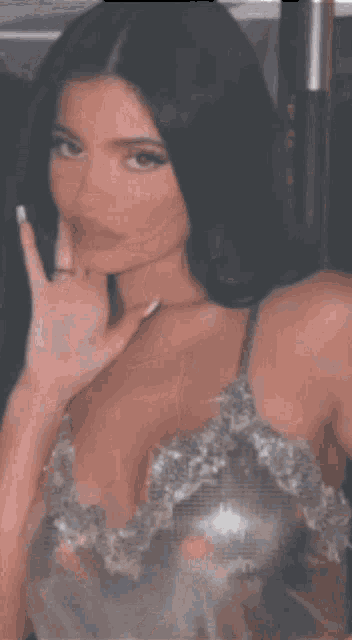 a woman in a silver dress is taking a picture of herself in a mirror .