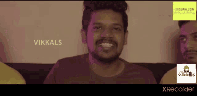 a group of men are sitting on a couch and one of them has the name vikkals written on his face