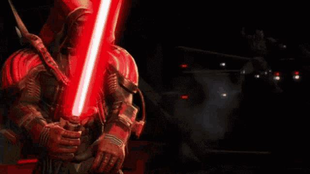 a man in a hood is holding a red light saber .
