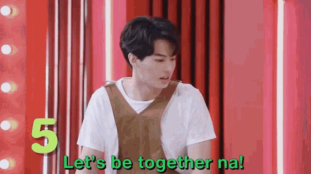 a man is standing in front of a red curtain and says let 's be together na .