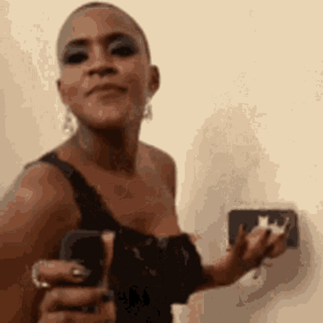 a woman in a black dress is holding a cell phone in her hand .
