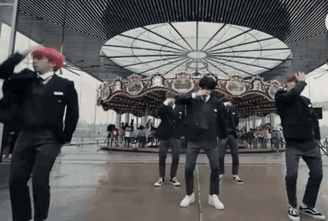 a group of people are dancing in front of a carousel