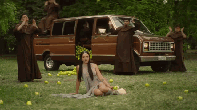 a woman sits in the grass in front of a van that has a license plate that says jcl - 88