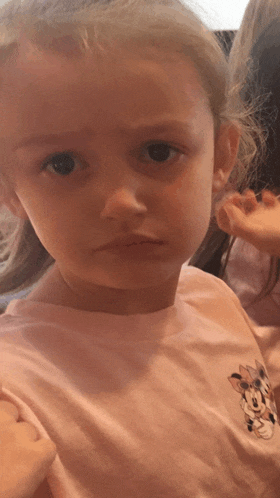 a little girl wearing a pink minnie mouse t-shirt