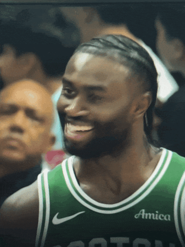 a man wearing a green jersey with the word amica on it smiles