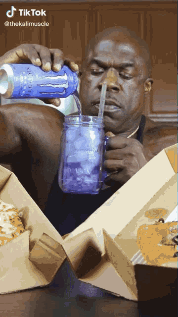 a man is drinking from a mason jar with a straw and a can of monster energy