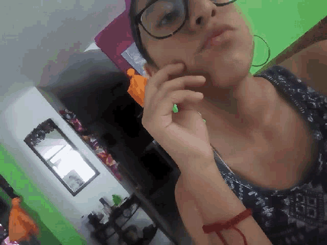 a woman wearing glasses and a red bracelet is taking a picture of herself