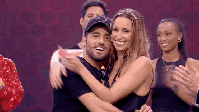 a man and a woman are hugging each other in front of a group of people .