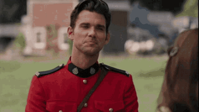 a man in a red uniform is standing in front of a horse
