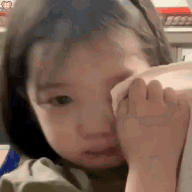 a little girl is crying and wiping her eyes with her hand .