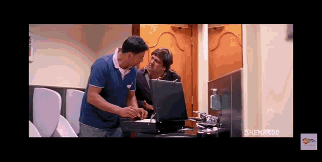 two men are talking in front of a computer screen that says snemaroon