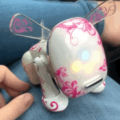 a person is playing with a white and pink toy dog with wings .