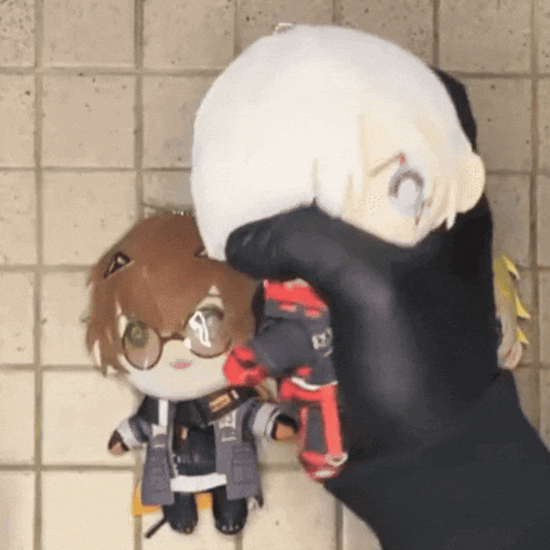 a person is holding two stuffed animals one of which has the letter c on its head