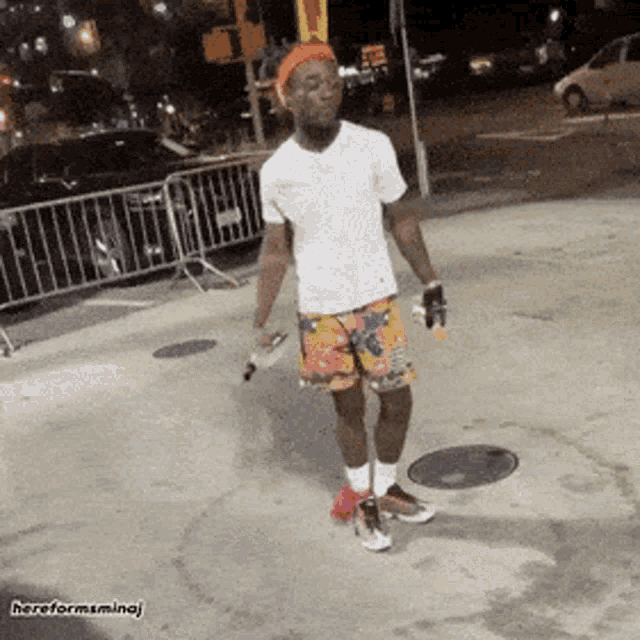 a man in a white shirt and colorful shorts is standing on the sidewalk