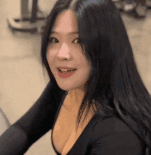 a woman with long black hair and a very plunging neckline is smiling and looking at the camera .