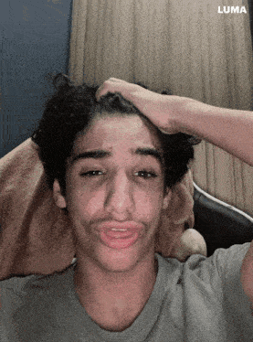 a young man is making a funny face with a luma logo in the background