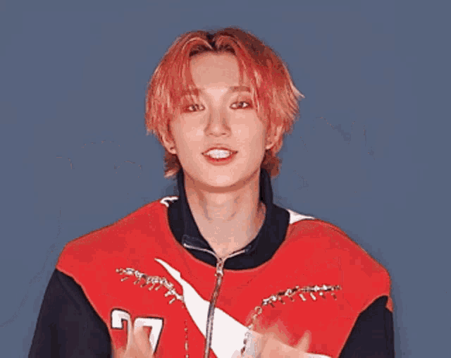 a young man with red hair wearing a red and white jacket with the number 77 on it