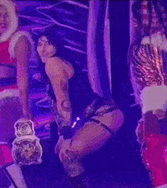 a woman is dancing on a stage with a man in a santa claus costume in the background .