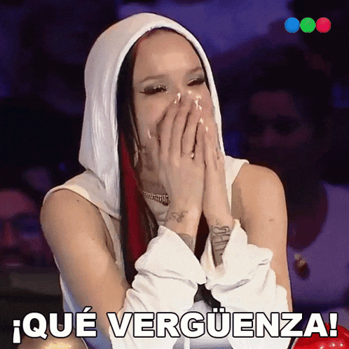 a woman in a white hoodie covering her mouth with her hands and the words que verguenza
