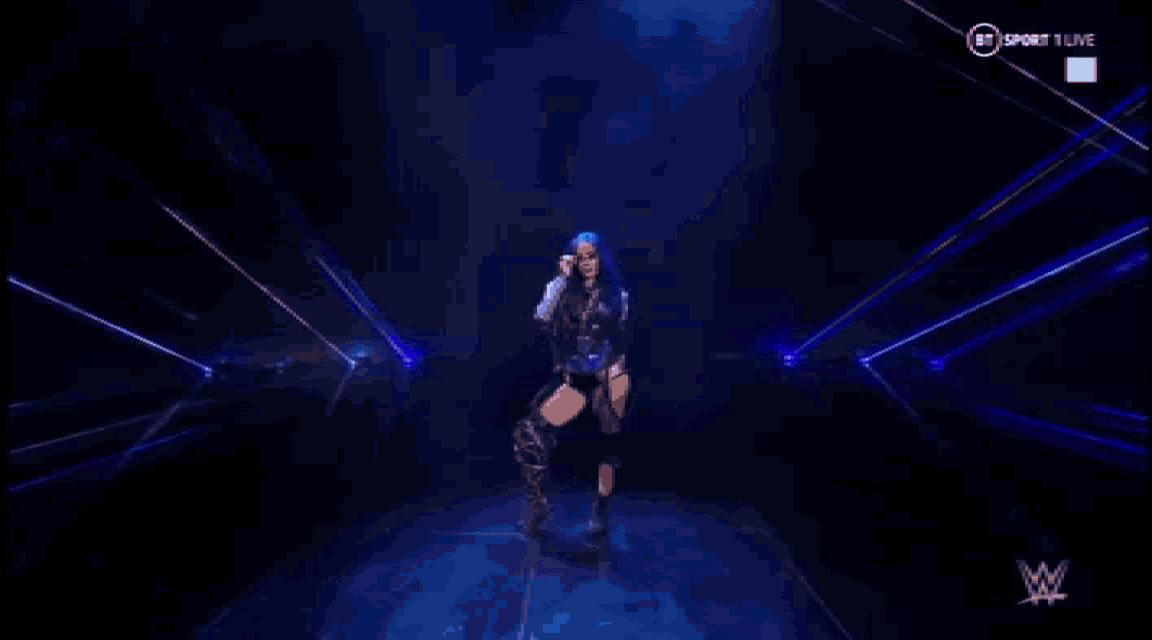 a female wrestler is standing in front of a blue light show .