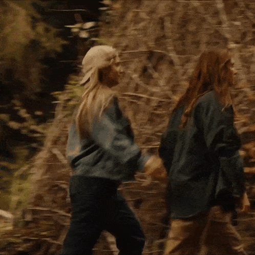 a couple of people hugging each other in a forest