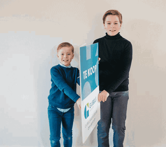 two young boys are holding a sign that says te koop