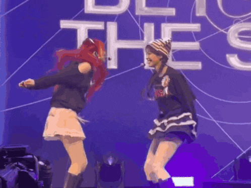 two girls are dancing on a stage in front of a sign that says " be the "