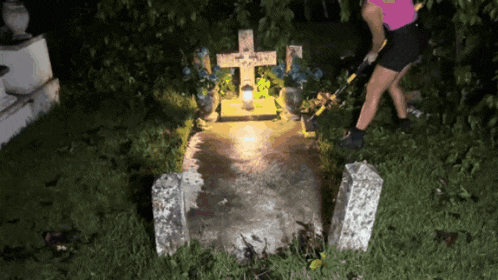 a woman stands in front of a grave with a cross and a candle on it