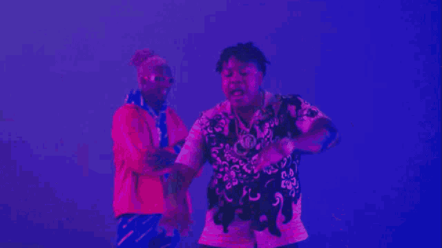 a man in a pink shirt is standing next to another man in a purple shirt