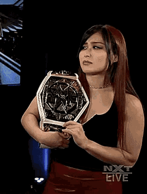 a woman in a black tank top is holding a wrestling championship belt .