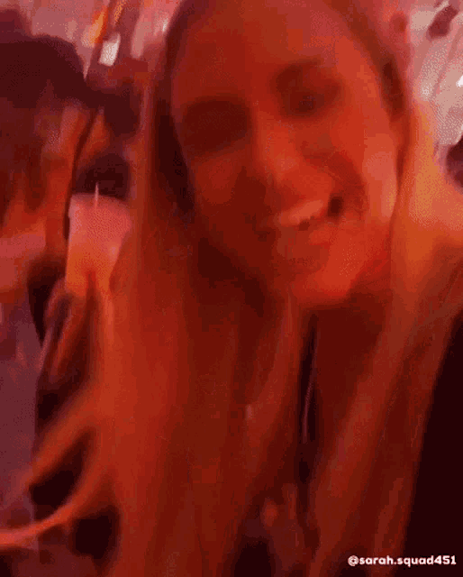 a woman is smiling in front of a crowd of people at a party