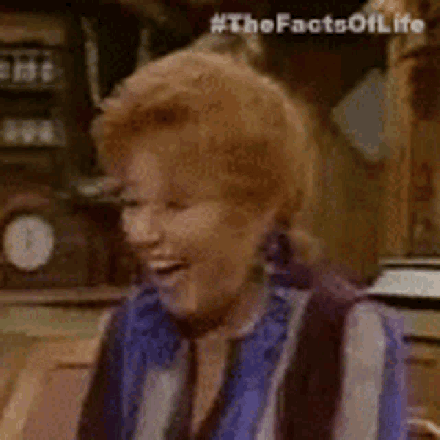 a woman in a blue and white striped shirt is smiling in a room with a clock in the background .