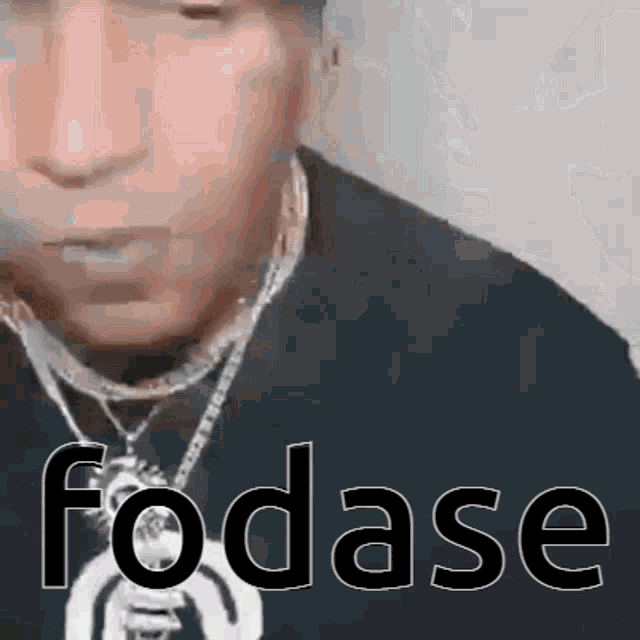 a man wearing a black shirt and a necklace with the word fodase written on it