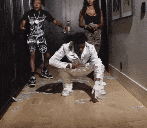 a man in a white jacket is kneeling on a wooden floor with money on the floor