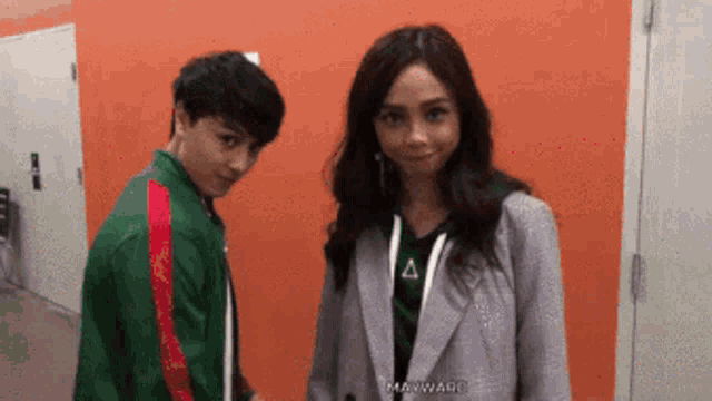 a man in a green jacket is standing next to a woman in a purple jacket .