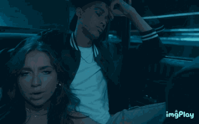 a man and a woman are sitting in the back seat of a car with imgplay written on the bottom right corner