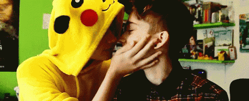 a man in a pikachu costume kisses another man on the cheek .